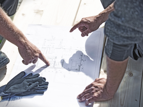 to menn på byggeplass som peker på byggetegning for byggteknisk prosjektering