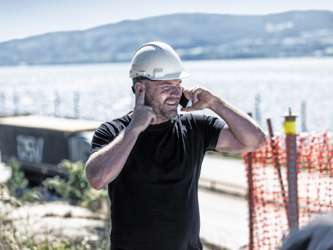 lydberegning er blant de tekniske tjenestene vi i Optimera kan tilby. Illustrasjonsbilde som viser håndverker på byggeplass, med forsøk på å holde støy ute.